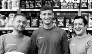 The team at Progrow Exeter pose in a hydro store, in front of shelves housing grow products.