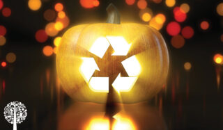 A yellow pumpkin with a blurry background is illuminated by a glowing recycling logo.