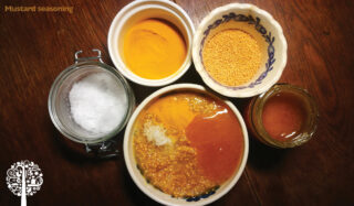 Mustard seasoning in clear, glass jars on a brown wooden table.