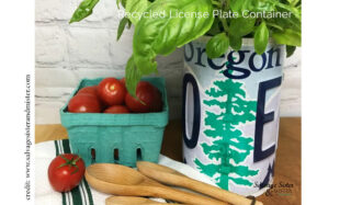 Recycled license plate container being used as a planter for a green plant, sitting beside a box of tomatoes and several wooden spoons.